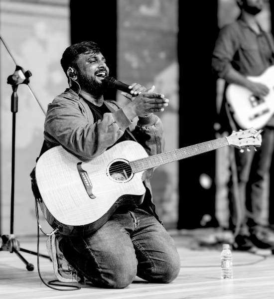Selvam kneeling worship with acoustic guitar